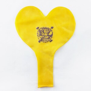 May include: A yellow heart-shaped balloon with a black and white graphic of two cartoon characters hugging. The graphic is surrounded by a circle of small hearts.