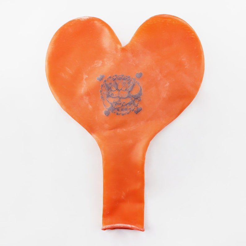 May include: An orange heart-shaped balloon with a black and white skull and crossbones design printed on it.