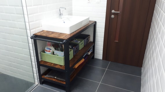Fregadero negro en un estante de madera en un baño moderno con