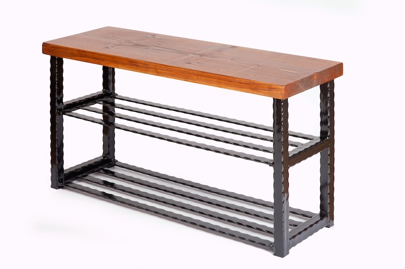 May include: A wooden shoe bench with a dark brown, rectangular top and a black metal frame. The bench has three horizontal metal bars for shoe storage. The wood top is a warm brown color.