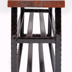 May include: A handcrafted bench with a dark stained wooden top and a black metal frame. The bench features a slatted design on the lower portion, providing a unique visual element. The wood top has visible grain.
