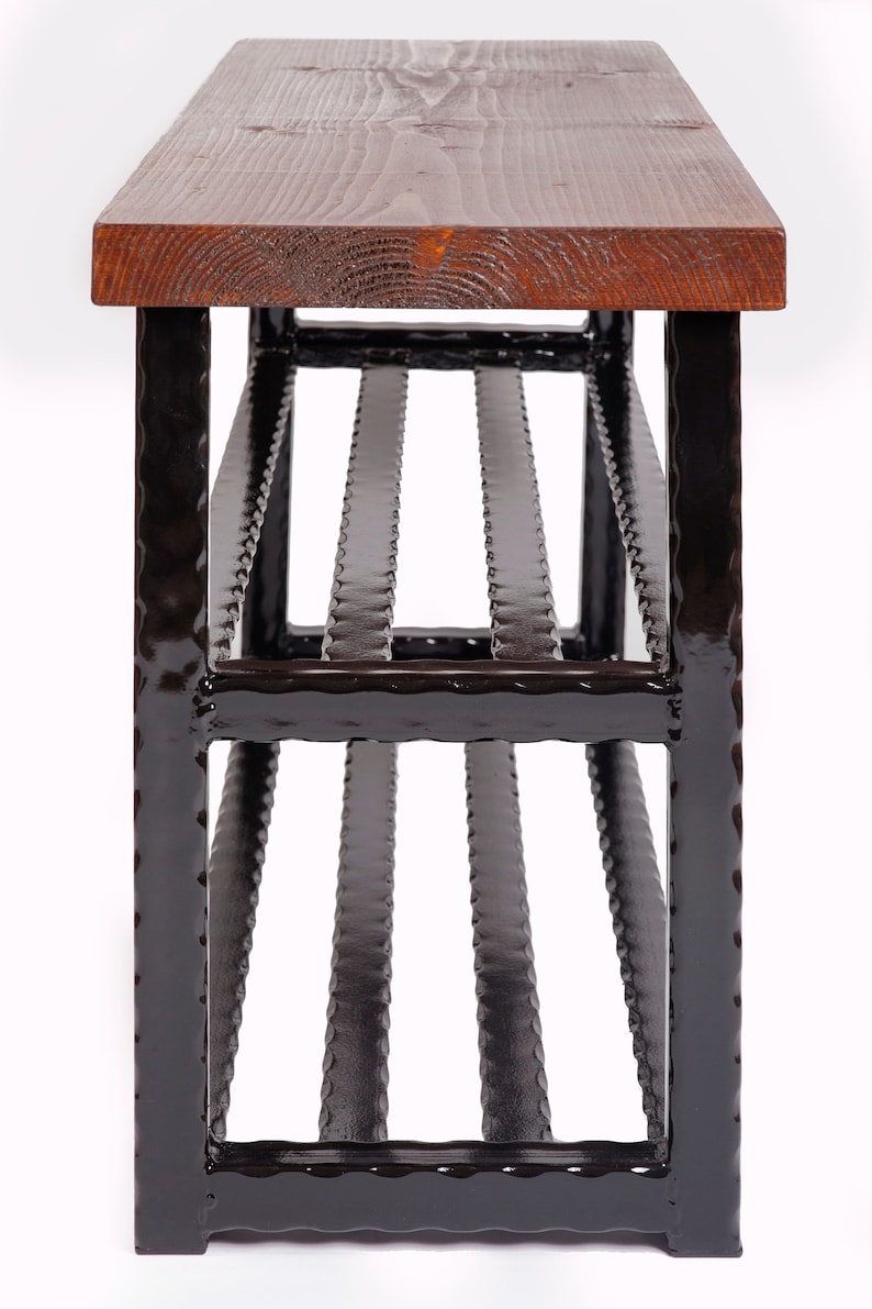 May include: A handcrafted bench with a dark stained wooden top and a black metal frame. The bench features a slatted design on the lower portion, providing a unique visual element. The wood top has visible grain.