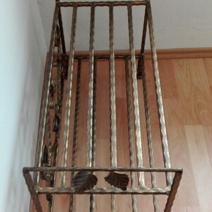 May include: A gold metal shoe rack with a decorative leaf design. The rack has multiple tiers for storing shoes.