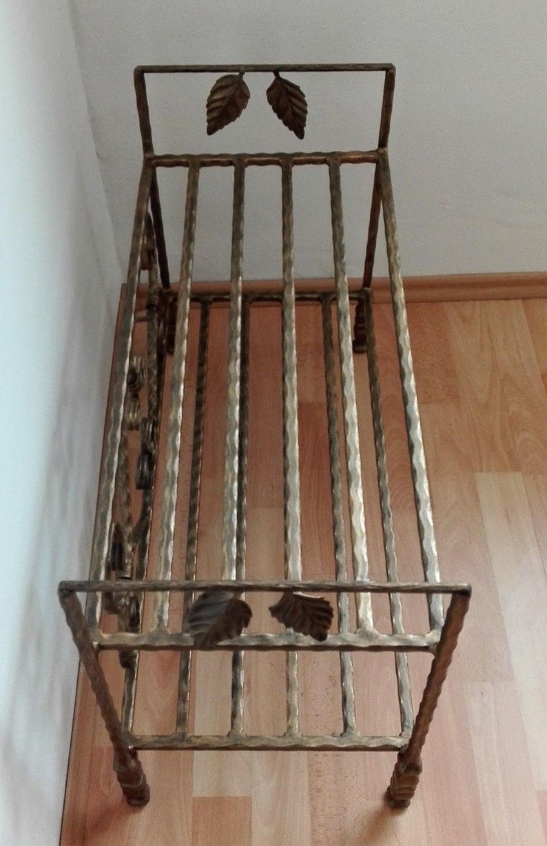 May include: A gold metal shoe rack with a decorative leaf design. The rack has multiple tiers for storing shoes.