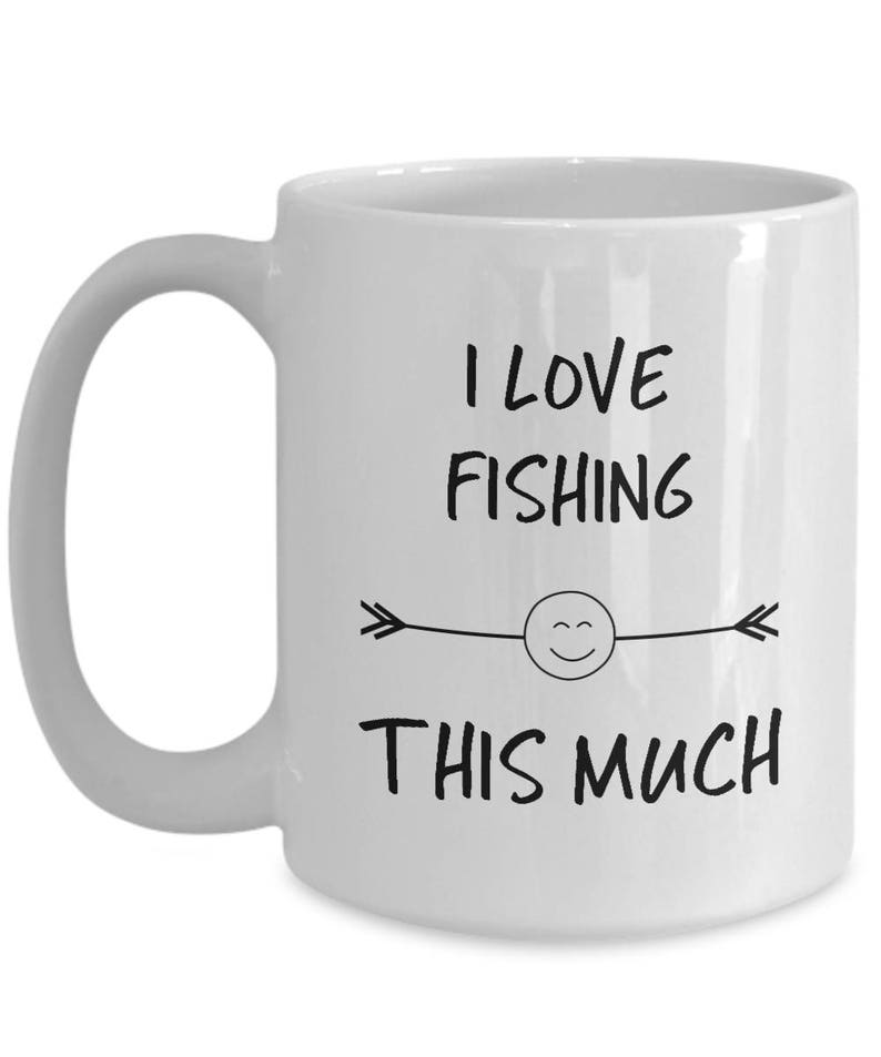May include: White ceramic coffee mug with a black design that says "I love fishing this much" with a smiley face and arrows on either side.