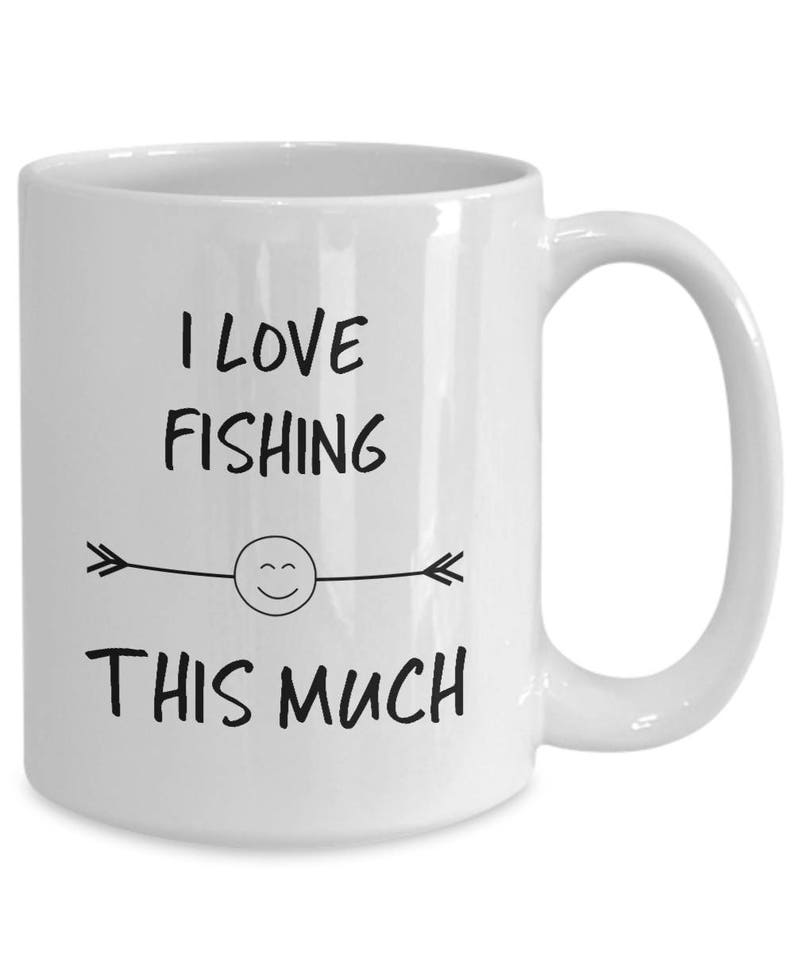 May include: White ceramic coffee mug with black text that reads "I love fishing this much" with a smiley face and arrows on either side.