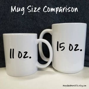 May include: Two white ceramic mugs, one 11 oz and one 15 oz, side by side. The mugs are both white with black handwritten text indicating their size.