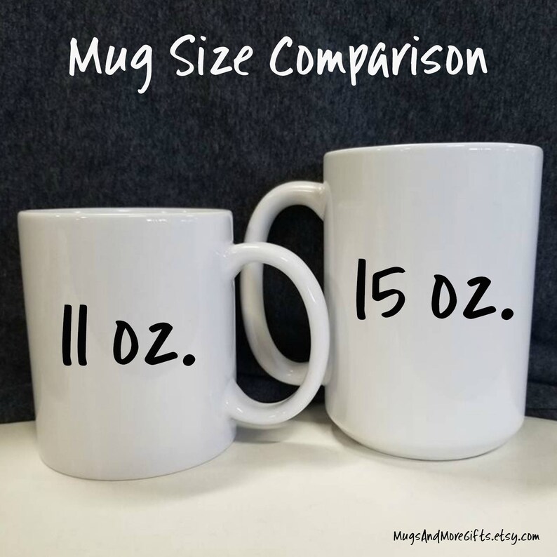 May include: Two white ceramic mugs, one 11 oz and one 15 oz, side by side. The mugs are both white with black handwritten text indicating their size.