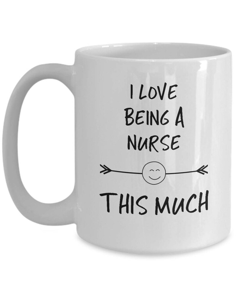 May include: White ceramic coffee mug with a black design that says "I love being a nurse this much" with a smiley face and arrows.
