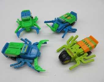 May include: Four toy bugs, each with a different colour scheme. One is green and blue, one is green and orange, one is green and black, and one is blue and green. The bugs have wheels and can be transformed into different shapes.