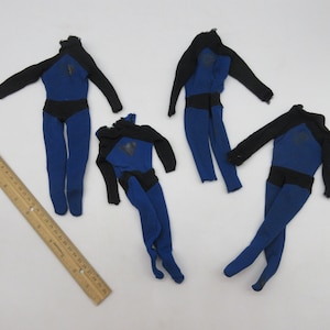 May include: Four blue and black fabric doll outfits. The outfits are made of a stretchy fabric and have a black belt around the waist. The outfits are in various positions on a white surface.