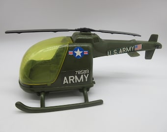 May include: Green toy helicopter with a clear plastic canopy, a U.S. Army sticker, and the number 78589. The helicopter has a black rotor blade and a white star on the side.