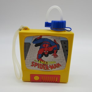 May include: A yellow plastic water bottle with a blue lid and a straw. The bottle has a picture of Spider-Man on the front with the text "The Amazing Spider-Man".