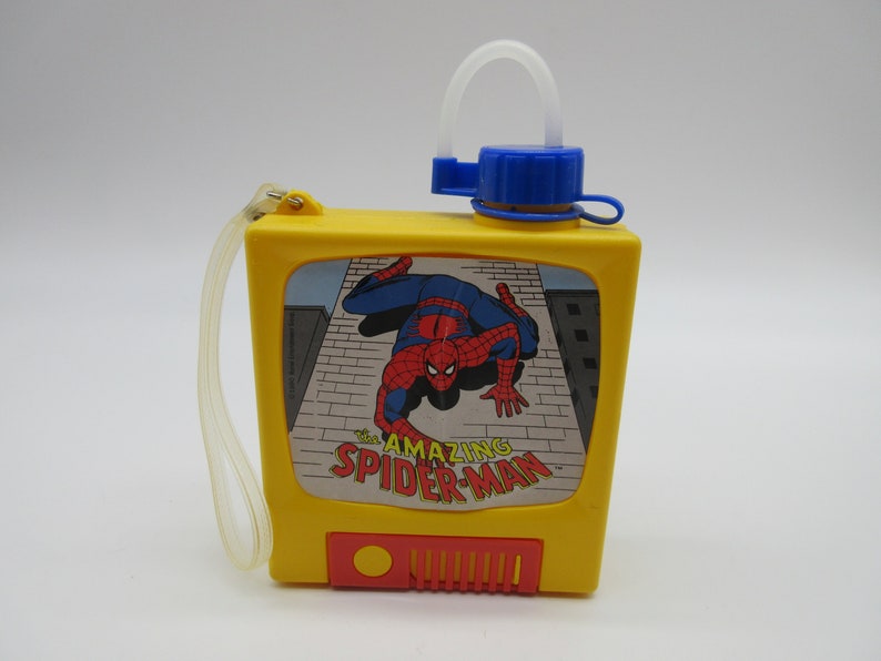 May include: A yellow plastic water bottle with a blue lid and a straw. The bottle has a picture of Spider-Man on the front with the text "The Amazing Spider-Man".