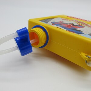 May include: Yellow plastic water bottle with a blue cap and a white straw. The bottle has a picture of Spiderman on the front with the text "Spider-Man".