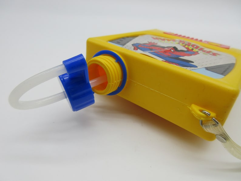 May include: Yellow plastic water bottle with a blue cap and a white straw. The bottle has a picture of Spiderman on the front with the text "Spider-Man".