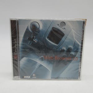 Könnte beinhalten: Versiegelte Dreamcast Web Browser 2.0 Spielhülle. Das Cover zeigt ein stilisiertes Bild eines Dreamcast-Controllers in Blau- und Grautönen. Der Text "Web Browser 2.0" ist prominent dargestellt, zusammen mit dem Dreamcast-Logo.