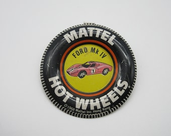 May include: A black and white Hot Wheels toy car tire shaped ashtray with the words "Mattel", "Ford MK IV", "Hot Wheels", and "©1968 Mattel Inc. Hong Kong" printed on it.