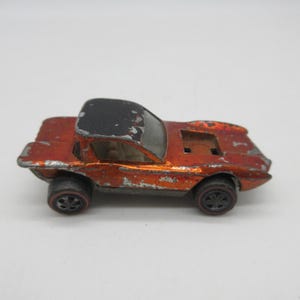 May include: A vintage orange and black toy car with red wheels. The die-cast metal car has a black roof and shows signs of wear, including paint chipping. The toy car is a classic collectible.