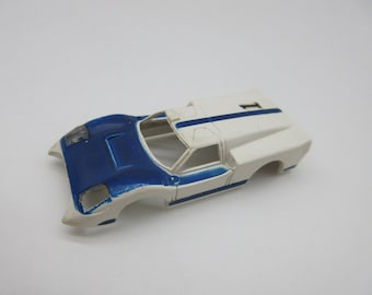 Pode incluir: Carroceria de carro modelo de plástico branco e azul, sem rodas ou interior. O carro tem uma faixa de corrida azul no centro do teto e o número "1" na parte traseira.