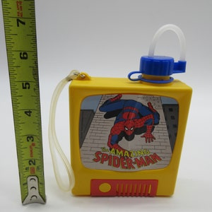 May include: Yellow plastic water bottle with a blue lid and a straw. The bottle has a picture of Spider-Man on the front with the text "The Amazing Spider-Man".
