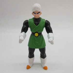 May include: A green and black action figure with a white headband. The figure has a yellow belt and white gloves.