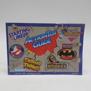 May include: A rectangular 1991 Kenner Starting Lineup Action Toy Guide booklet featuring colorful graphics and logos for The Real Ghostbusters, Bill & Ted's Excellent Adventure, The Dark Knight Collection, Swamp Thing, and Beetlejuice on a gray background.