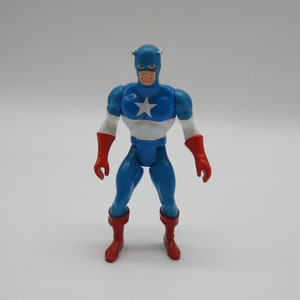 May include: A blue and red plastic action figure of Captain America. The figure has a white star on its chest and is wearing a blue helmet with a red stripe.
