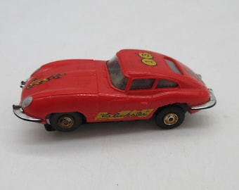 Pode incluir: Um carro de corrida de brinquedo vermelho com o número "61" no teto e o nome "Slickster" na lateral. O carro tem pneus pretos e um para-choque prateado. É um brinquedo vintage.