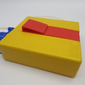 May include: Yellow plastic water bottle with a red and yellow lid and a blue spout. The bottle has a clear plastic tube attached to the spout.