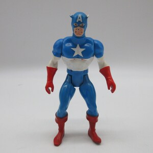 May include: A vintage action figure of Captain America, wearing his iconic red, white, and blue costume. The figure has a red helmet with a white star and the letter "A" on the front. The figure is standing with its arms at its sides.