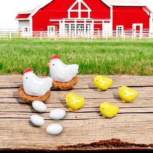 May include: A rustic scene featuring ceramic farm animals. Two white hens with red combs sit on nests, surrounded by yellow chicks and white eggs. A red barn and green field form the background.