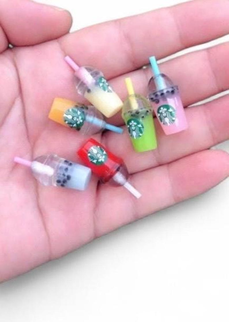 Pu&ograve; includere: Miniature tazze colorate di bubble tea con cannucce. Le tazze sono in vari colori, tra cui rosa, verde, giallo e rosso. Ogni tazza ha un logo Starbucks.