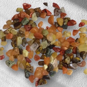 May include: A collection of small, colorful gemstone beads in shades of orange, yellow, red, and green. The beads are irregular in shape and have holes for stringing. The gemstones appear to be polished and have a natural, earthy look.