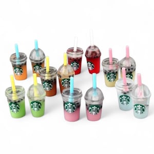 Pu&ograve; includere: Una collezione di mini bevande al bubble tea in vari colori, tra cui verde, arancione, marrone, rosa e rosso. Ogni bevanda ha un bicchiere di plastica trasparente, una cannuccia e un logo Starbucks. Le bevande sono disposte su sfondo bianco.