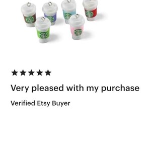 May include: Miniature coffee cup charms with white lids and colorful sleeves. The sleeves are in various colors, including green, pink, blue, and red. Each charm has a silver loop at the top.
