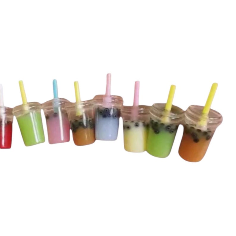 Pu&ograve; includere: Una collezione di mini bevande al t&egrave; alle bolle in vari colori, tra cui verde, rosa e arancione. Ogni bevanda &egrave; in un bicchiere di plastica trasparente con una cannuccia abbinata e perle di tapioca scure.