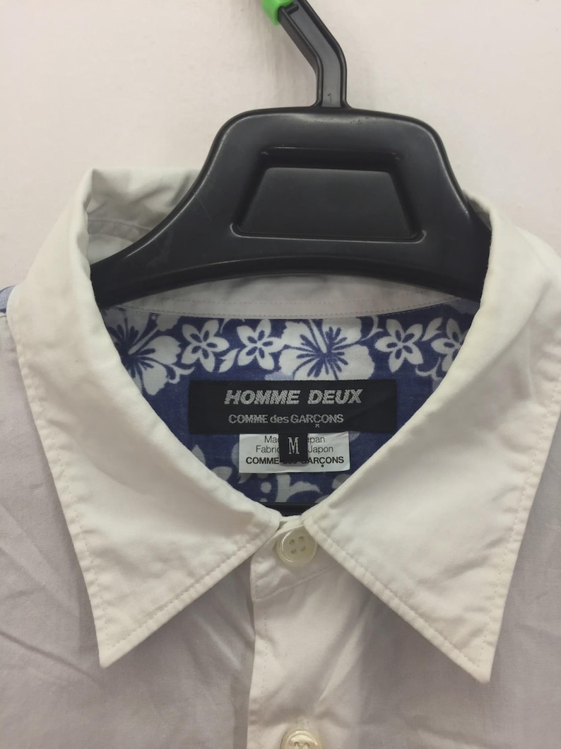 Puede incluir: Una taza de cer&aacute;mica blanca con un asa negra y el texto "But First, Coffee" en negro, con una fuente de estilo manuscrito. La taza est&aacute; sobre una superficie blanca.