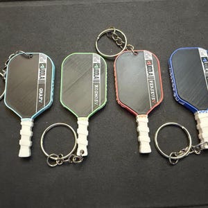 May include: A set of three ceramic mugs with a speckled, matte finish. The mugs are in shades of blue, green, and gray. Each mug has a simple, modern design, perfect for coffee or tea. The mugs are stacked on top of each other.