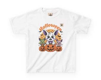 May include: White t-shirt with a Halloween-themed graphic. The design shows three cartoon creatures on carved pumpkins, with the word "Halloween" above. The creatures are coloured green, pink, and white.