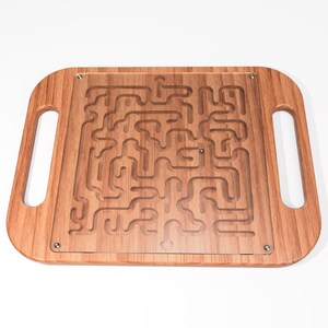 May include: A wooden maze game with a clear acrylic top. The maze is carved into the wood and has a small metal ball that can be rolled through the maze.