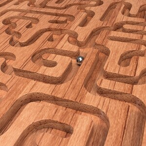 May include: A wooden maze with a silver ball in the center. The maze is made of wood and has a natural wood grain finish.