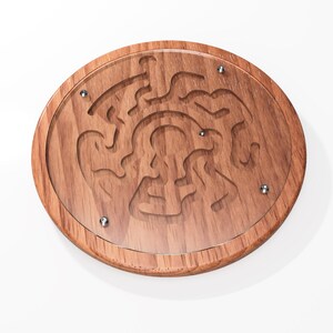 May include: A wooden circular maze game with a clear acrylic top. The maze is carved into the wood and has a complex design. There are five metal balls that can be used to navigate the maze.