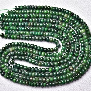 Op de afbeelding: Een streng groene edelsteen kralen, ongeveer 4 mm groot, met een gladde, gepolijste afwerking. De kralen zijn geregen op een dun draad en zijn klaar voor het maken van sieraden.