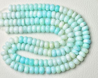 May include: Strands of light blue and white gemstone beads. The beads are oval-shaped and strung together, creating a flowing, organic pattern. The color gradient ranges from pale white to a vibrant turquoise.
