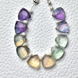 May include: A strand of faceted gemstone beads in a gradient of purple, blue, green, and yellow. The beads are separated by small white beads.