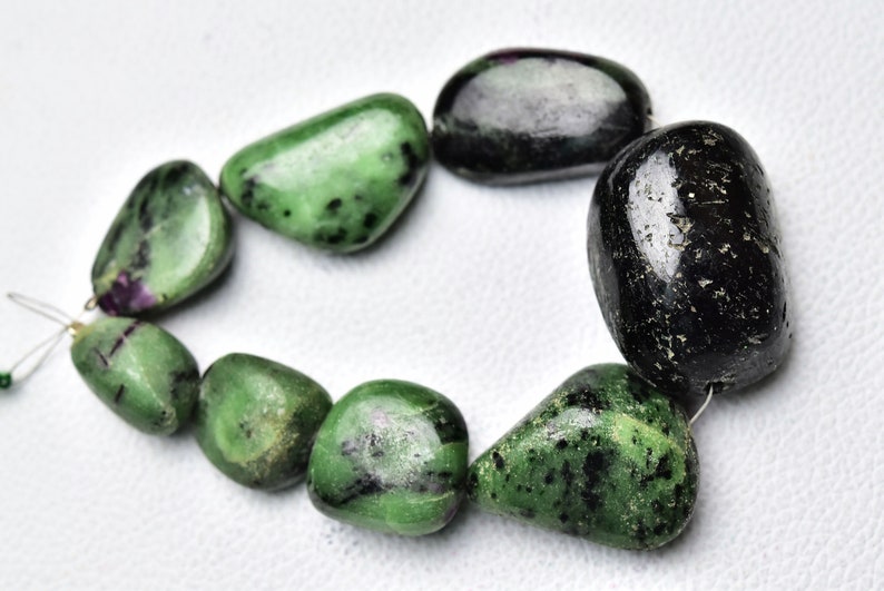 May include: A strand of green and black gemstone beads. The beads are smooth and polished, and they have a natural, organic look. The beads are strung on a thin wire.