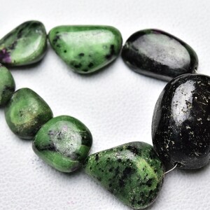 May include: A strand of green and black gemstone beads. The beads are smooth and polished, and they have a natural, organic look. The beads are strung on a thin wire.