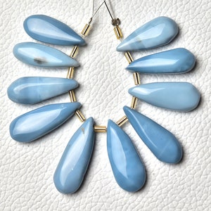 Peut inclure: Un brin de 10 perles d'opale bleue en forme de larme, chacune avec une surface lisse et polie. Les perles sont enfilées sur un fil d'or et sont prêtes à être utilisées pour la fabrication de bijoux.
