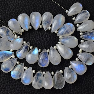May include: A strand of iridescent white moonstone beads in a teardrop shape. The beads are strung on a silver wire with small silver spacers between each bead.